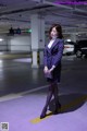 A woman in a purple suit standing in a parking garage.