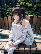 A woman sitting on a wooden bench in a park.