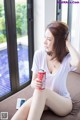 A woman sitting on a couch holding a can of soda.