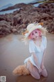 A woman in a white dress and a straw hat on a beach.