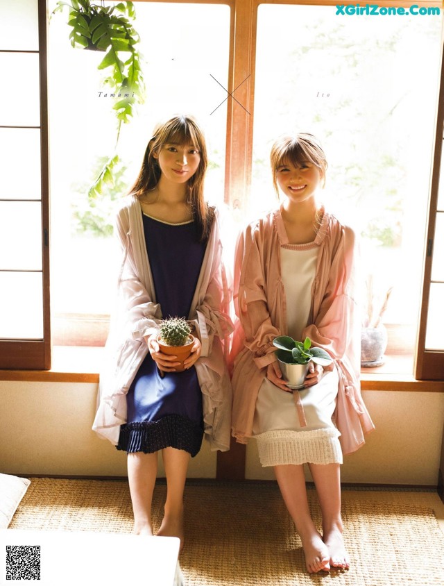 A couple of women standing next to each other in front of a window.
