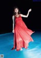 A woman in a red dress standing in the water.