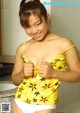 A woman in a yellow top and white panties posing for the camera.