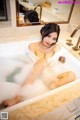 A woman sitting in a bathtub with foam in it.