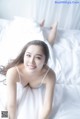 A woman laying on top of a white bed.