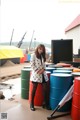 A woman standing in front of a bunch of colorful barrels.