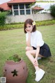 A woman sitting on the grass next to a flower pot.