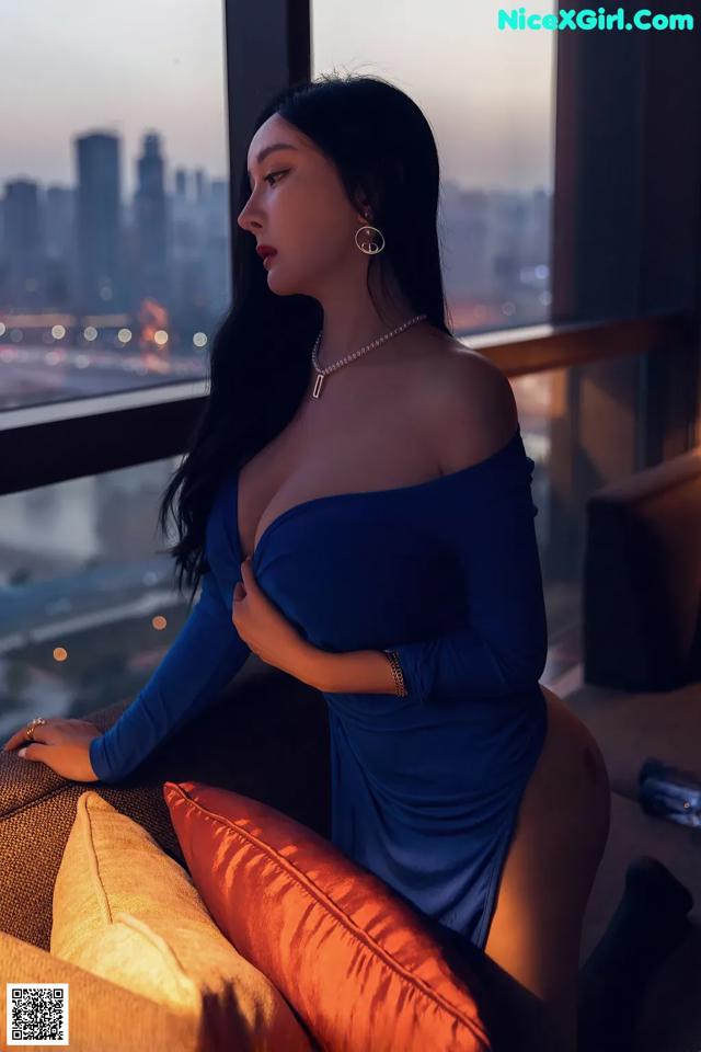 A woman in a blue dress sitting on a couch.