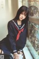 A woman in a school uniform sitting on a window sill.