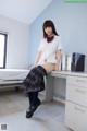 A woman in a school uniform sitting on a desk.